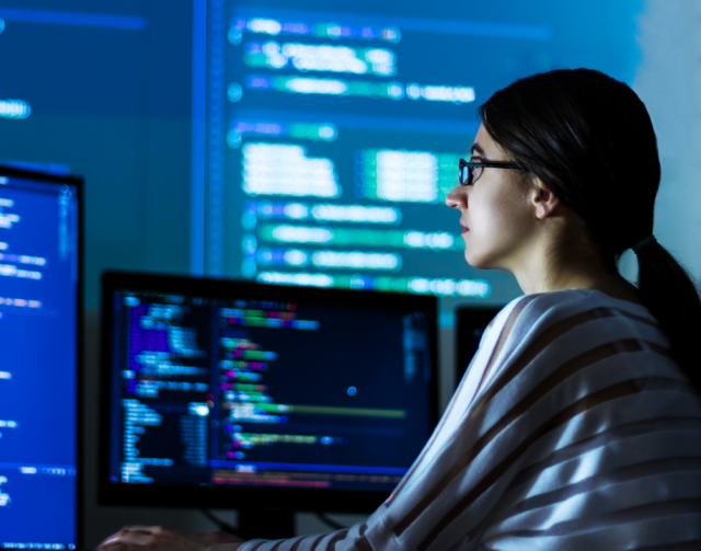 Woman with glasses at computer writing code