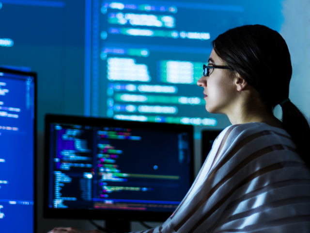 Woman with glasses at computer writing code